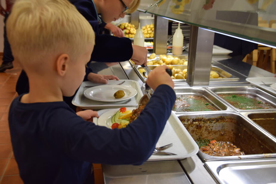 The boy chooses school food from the line.