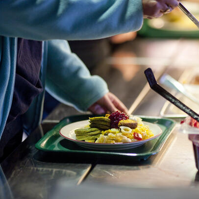 A student taking food on their plate at the school restaurant