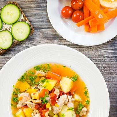 Chicken soup served with salad, bread and a drink.